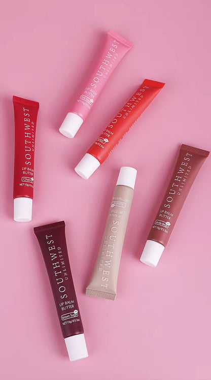 SOUTHWEST UNLIMITED lipbutters in assorted colors displayed on a wooden surface with soft lighting.